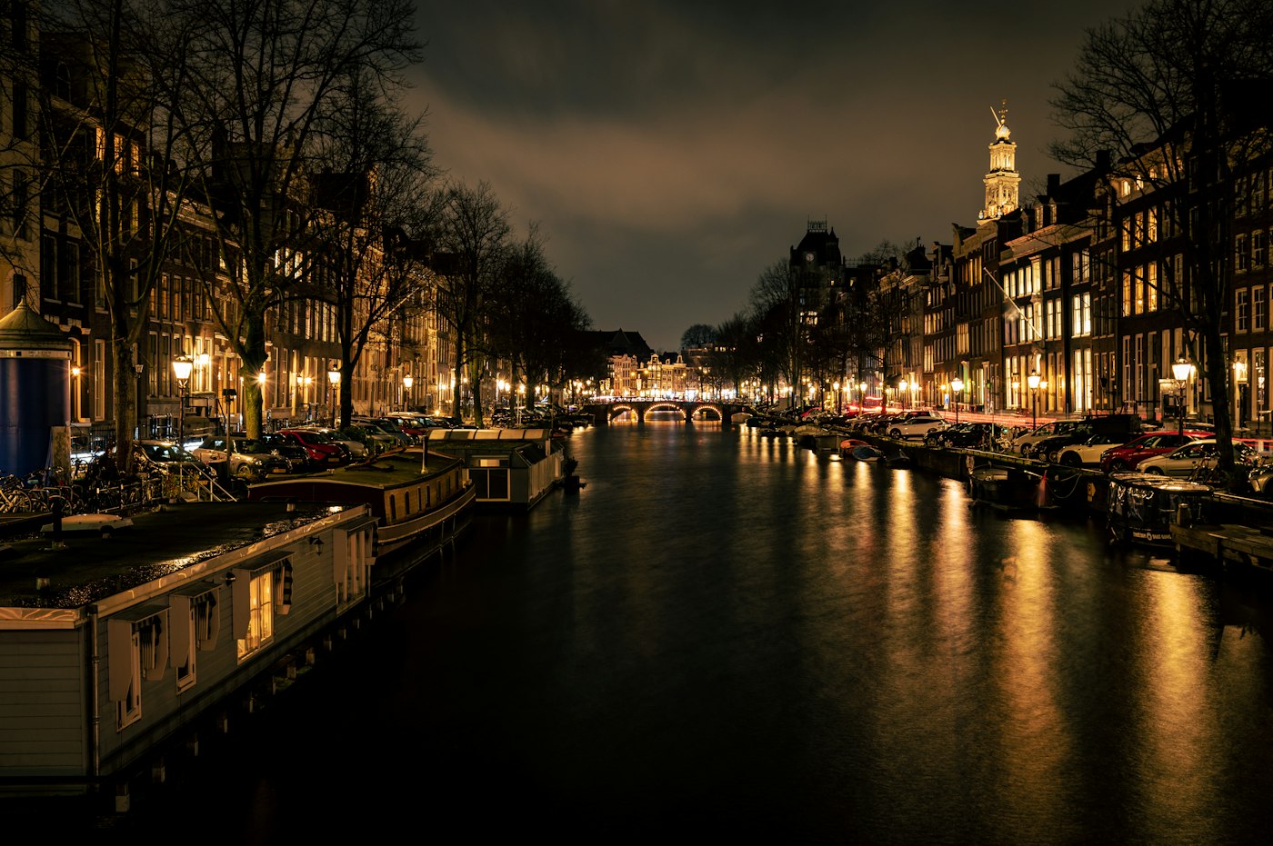 Un canale di Amsterdam di notte con i riflessi degli edifici illuminati nell’acqua